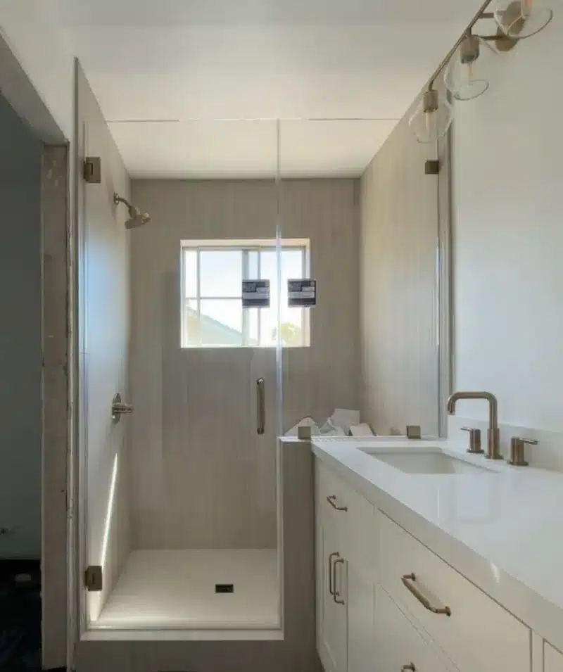 Brushed bronze frameless shower door and inline panel installed in San Clemente