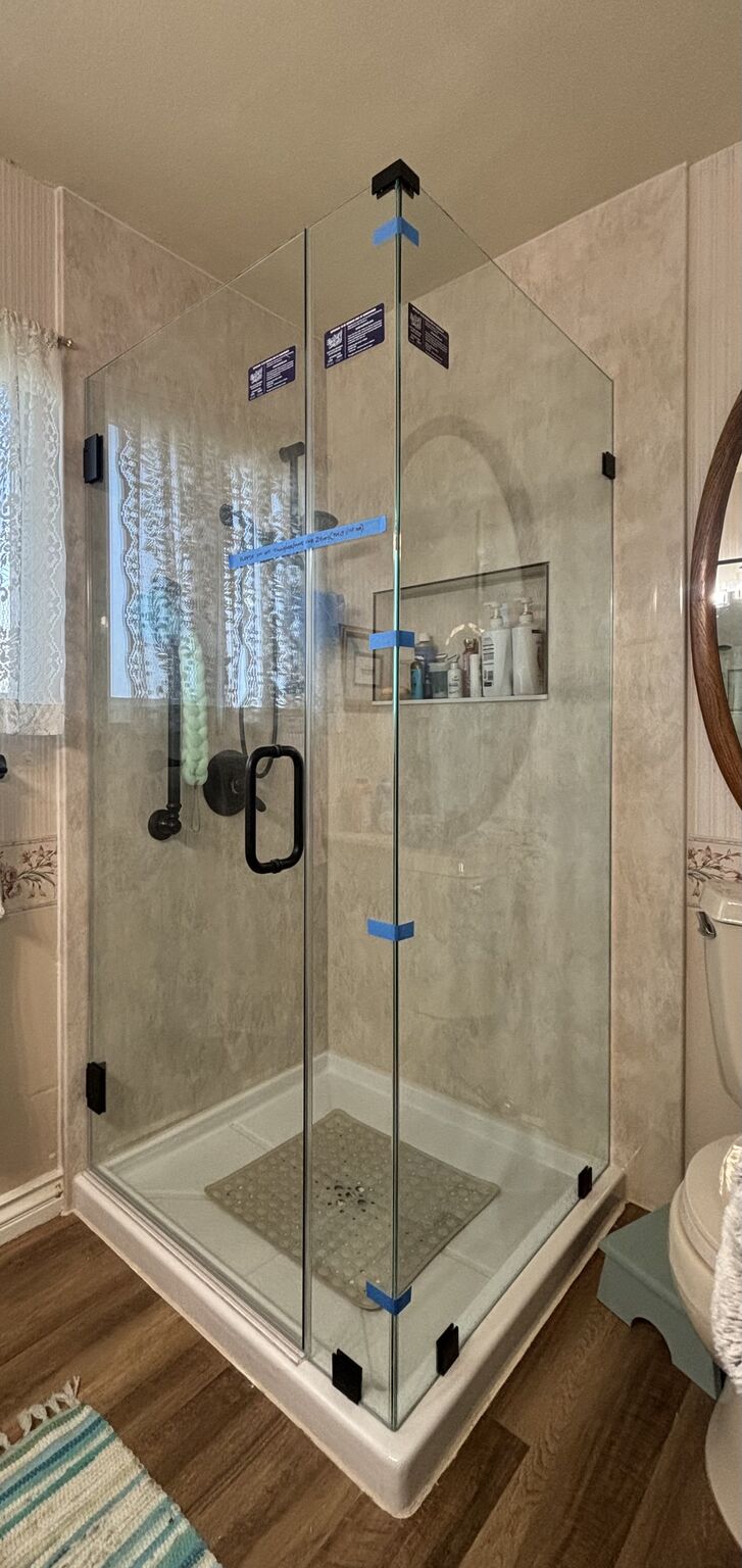 Clear frameless corner shower with dark hinges and handle in Chula Vista