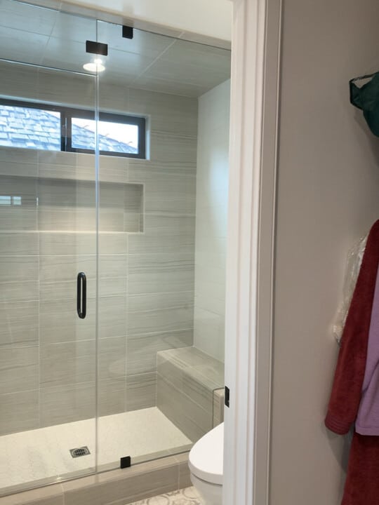 Floor-to-ceiling frameless shower door and inline panel with a transom in Huntington Beach