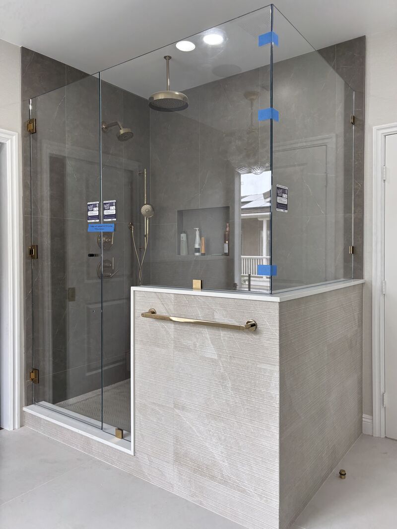 Opti-White low-iron frameless corner shower enclosure with French gold hardware installed in Huntington Beach