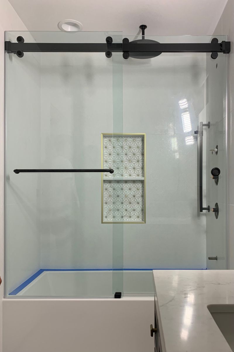 Matte-black double Euroglide sliding shower enclosure installed on an acrylic tub in Huntington Beach
