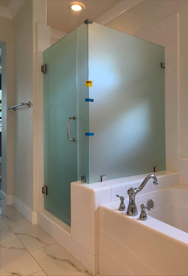 Frosted privacy-glass corner shower enclosure installed on an Irvine tub deck