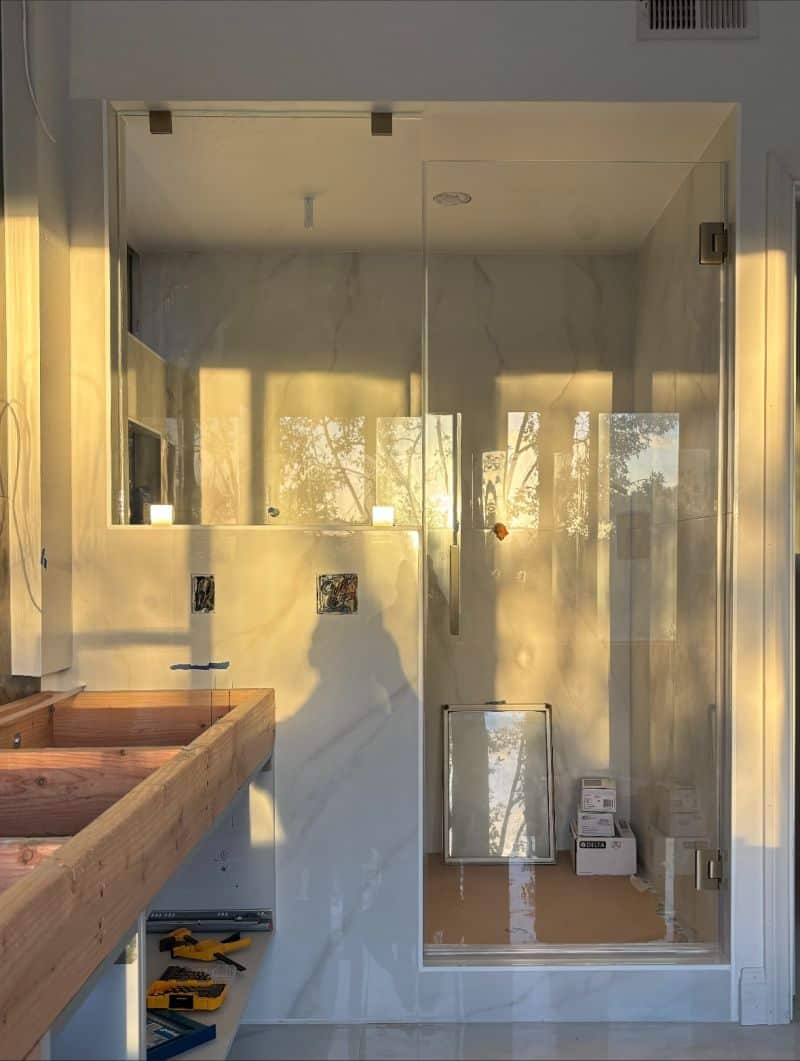 Frameless shower door and fixed inline panel on a pony wall extending to the ceiling in Laguna Niguel