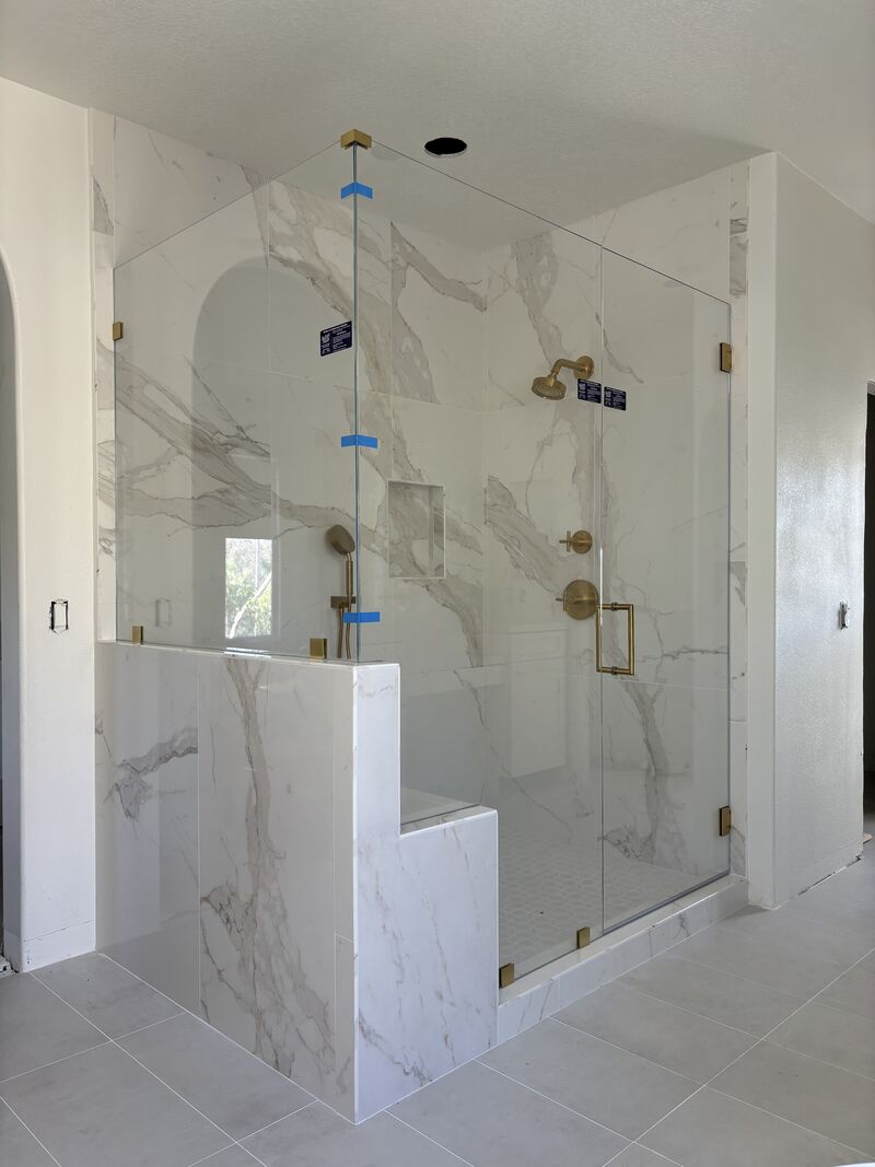 Opti-White frameless shower enclosure with satin-brass hardware, bench and pony-wall notches in Laguna Niguel