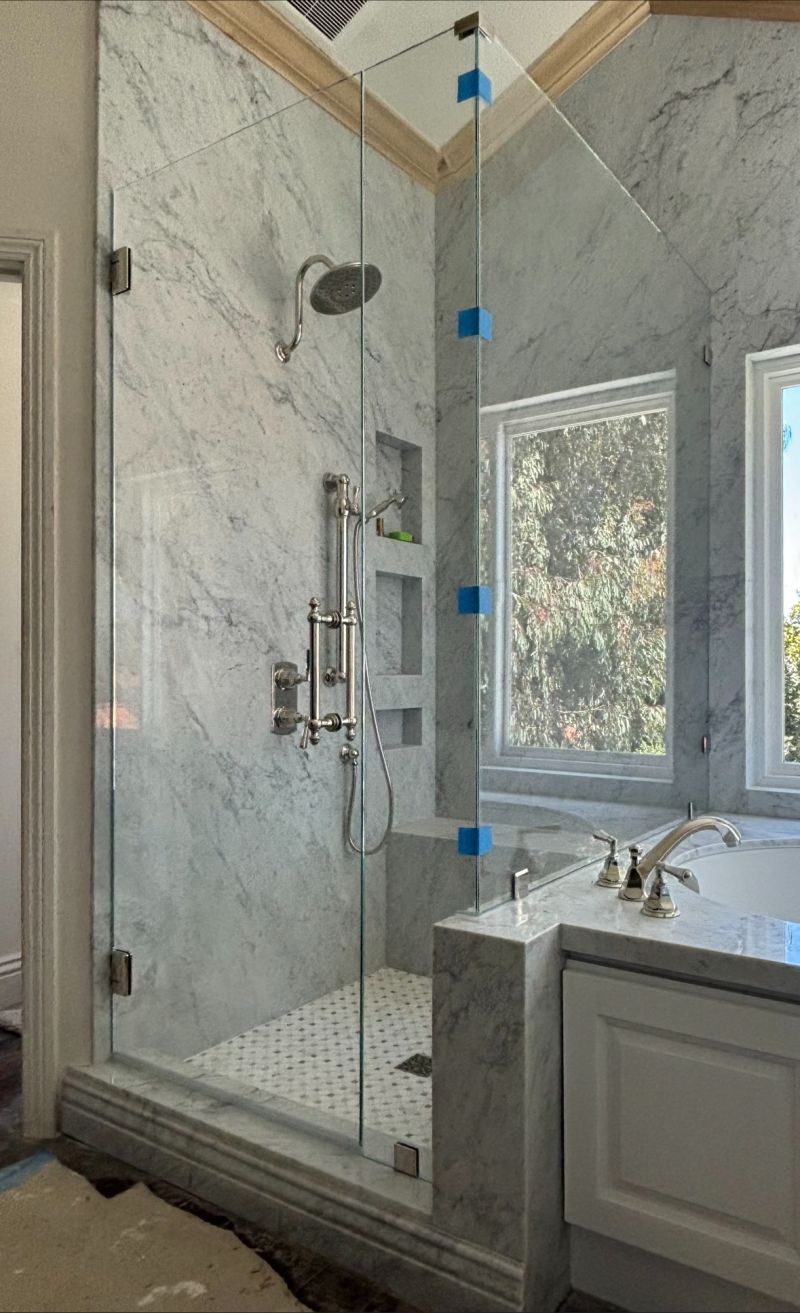 Starphire low-iron corner shower enclosure on a tub deck with polished-nickel hardware in Laguna Niguel