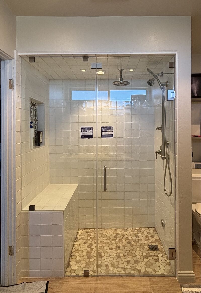 Floor-to-ceiling frameless steam shower enclosure with a pivoting transom in Laguna Niguel