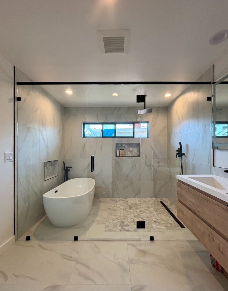 Wide frameless shower enclosure with two 117-pound stationary panels and a support header in Long Beach