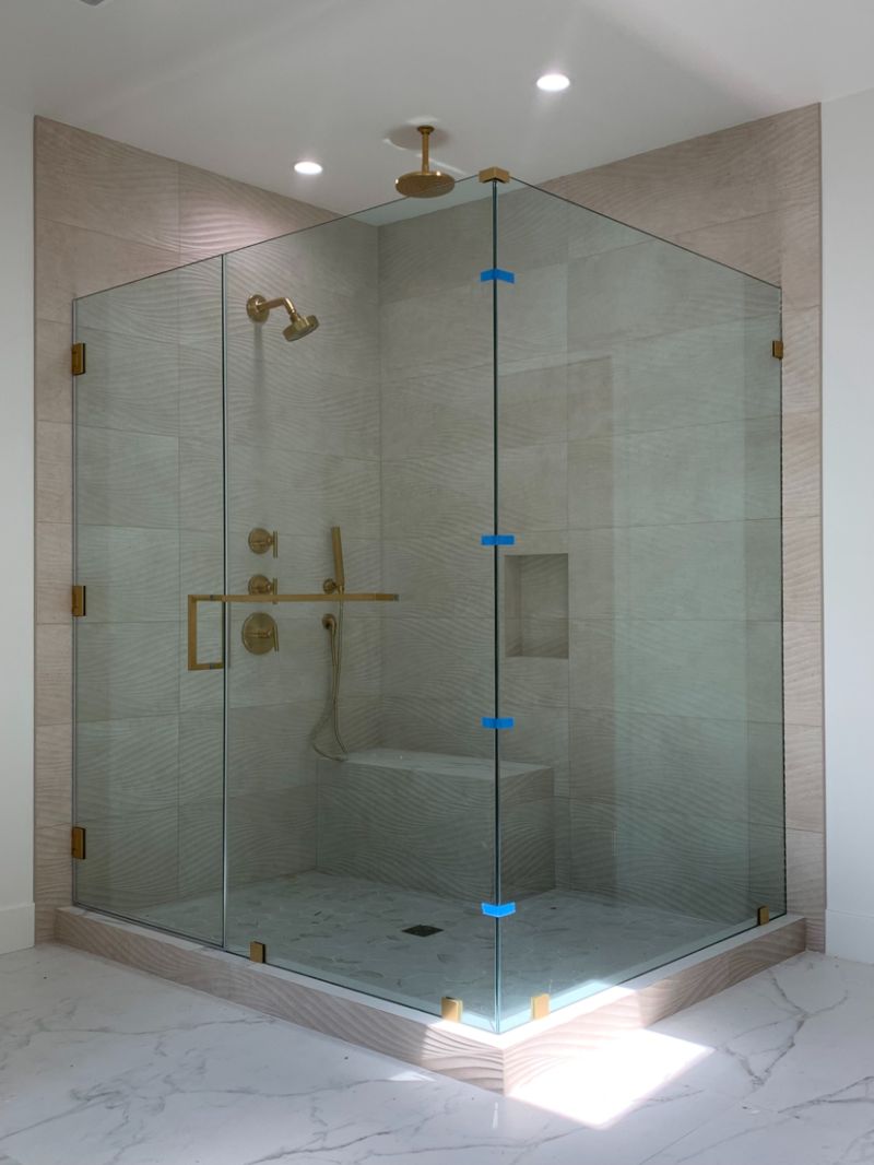 Finished frameless corner shower enclosure with 207-pound return panel and timeless-brass hardware in Manhattan Beach