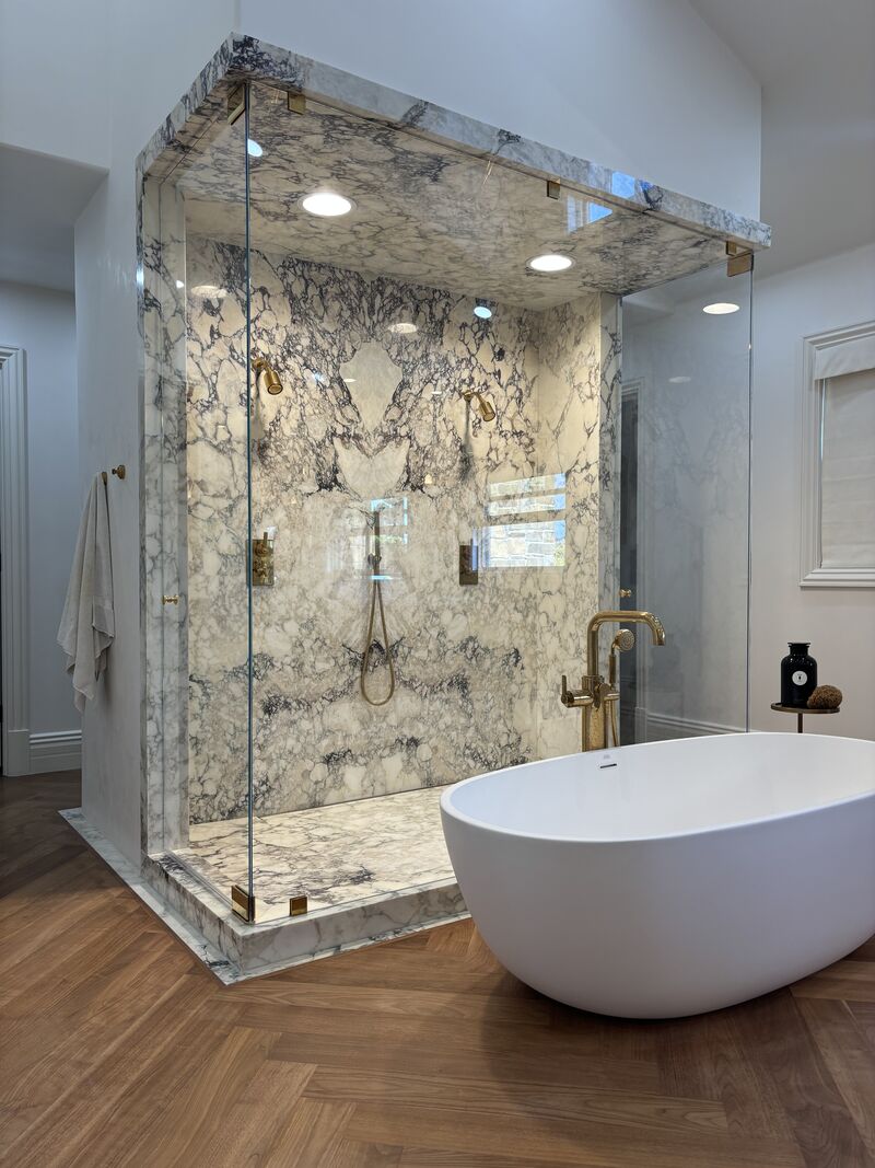 Oversized U-shaped floor-to-ceiling frameless shower enclosure with two pivot doors in Newport Beach