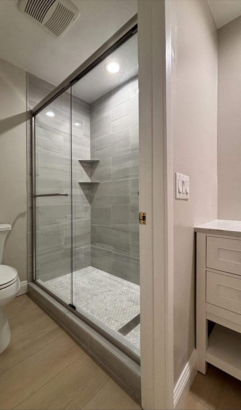 Brushed-nickel bypass sliding shower enclosure installed over a tub in Newport Beach