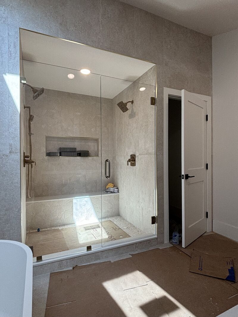 Bright Opti-White low-iron door-and-inline shower enclosure with frameless hardware in Newport Beach