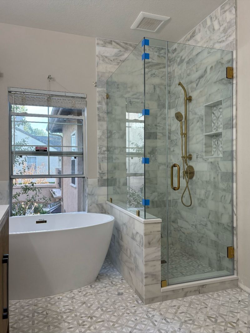 Frameless corner shower enclosure on a pony wall with Timeless brass hardware in Newport Beach