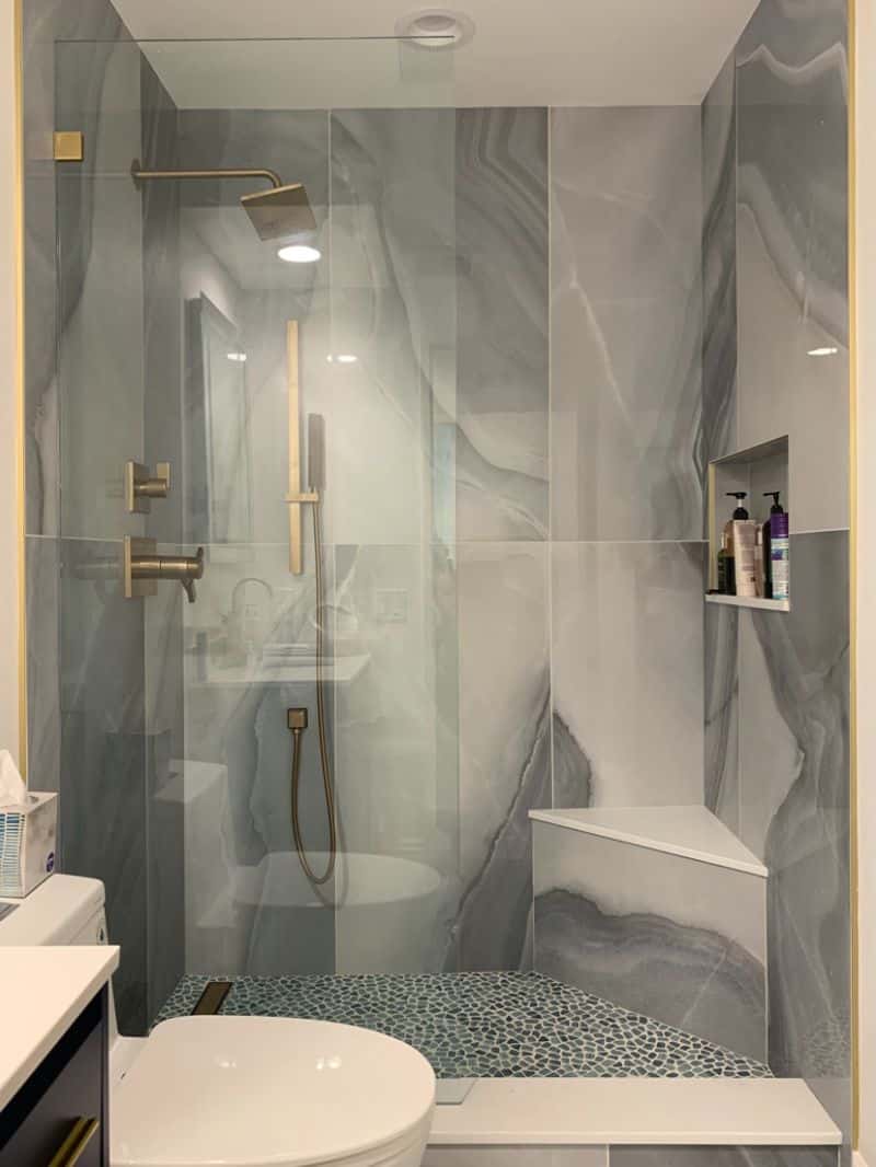 Fixed frameless shower splash panel with Timeless brass hardware in Newport Beach