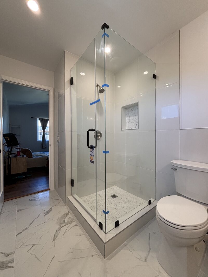 Clear frameless corner shower with dark hardware in Oceanside