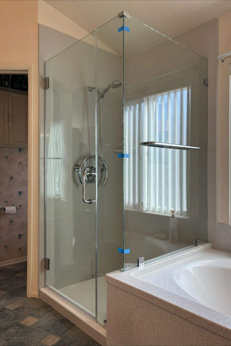 Frameless corner enclosure with a return panel above a tub deck in Oceanside