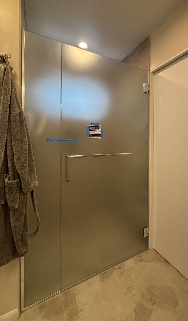Frosted privacy-glass door and inline panel for a curbless shower