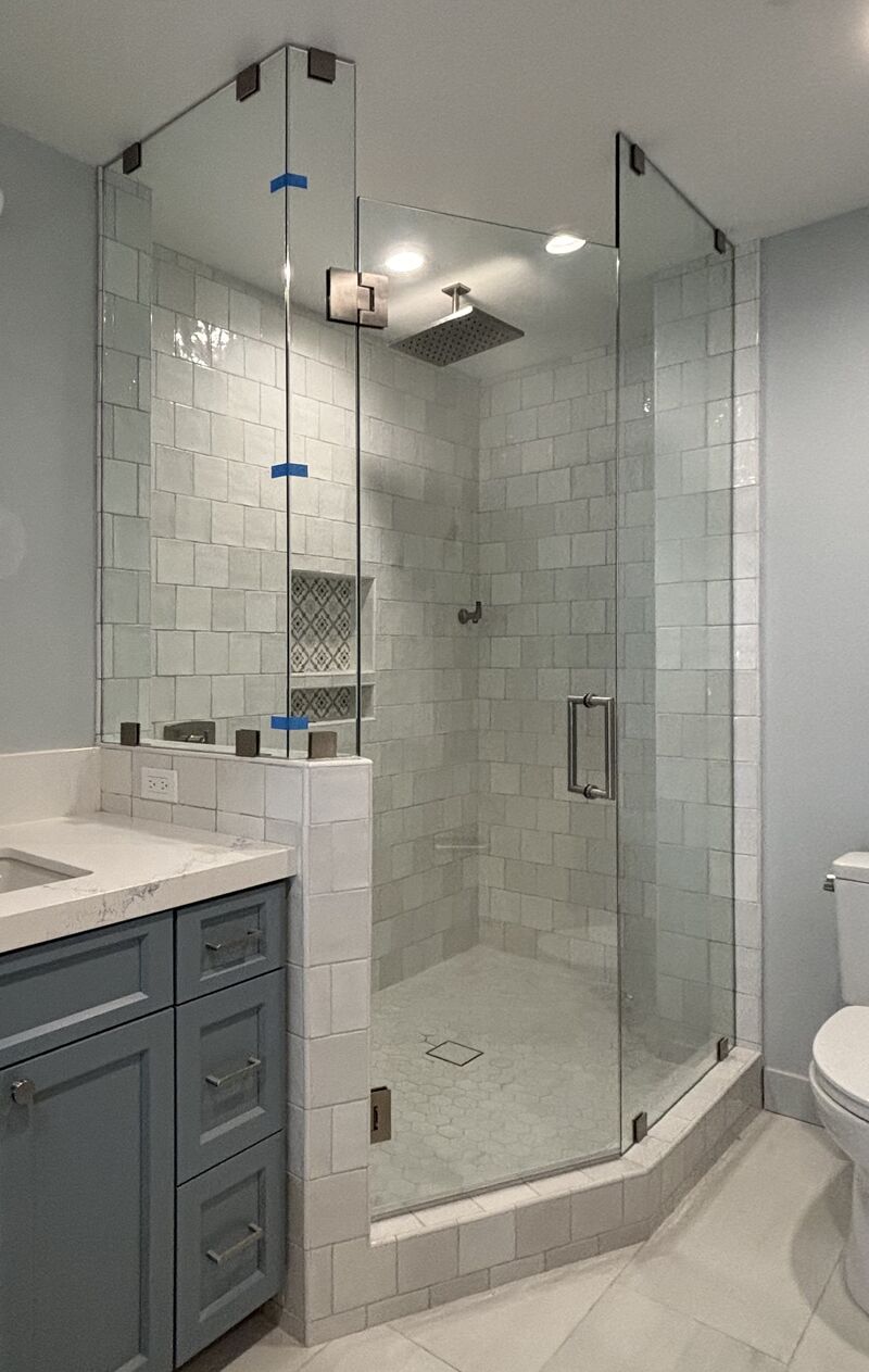 Floor-to-ceiling angled enclosure with offset pony-wall clamps in San Diego