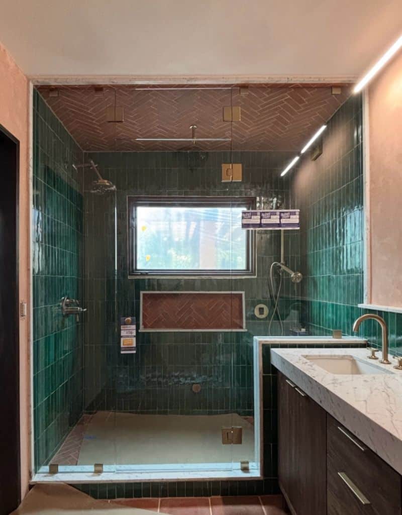 Floor-to-ceiling steam enclosure with movable transom and satin-brass hardware in San Diego