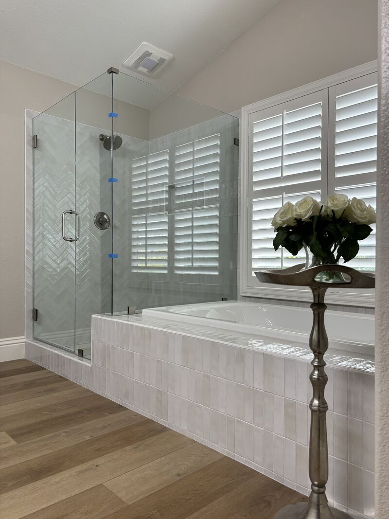 Finished frameless corner shower beside a tiled tub deck in San Diego