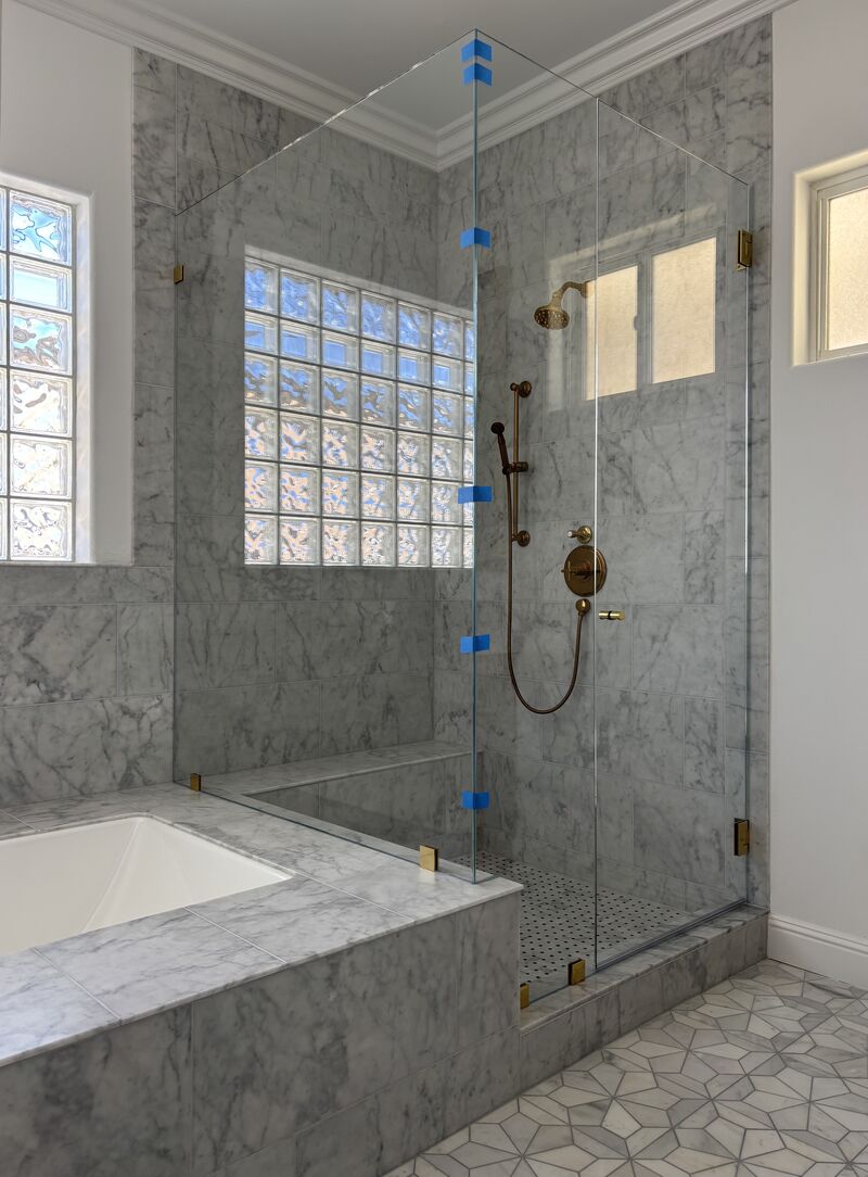 Opti-White low-iron frameless corner shower enclosure with unlacquered brass hardware in Sunset Beach