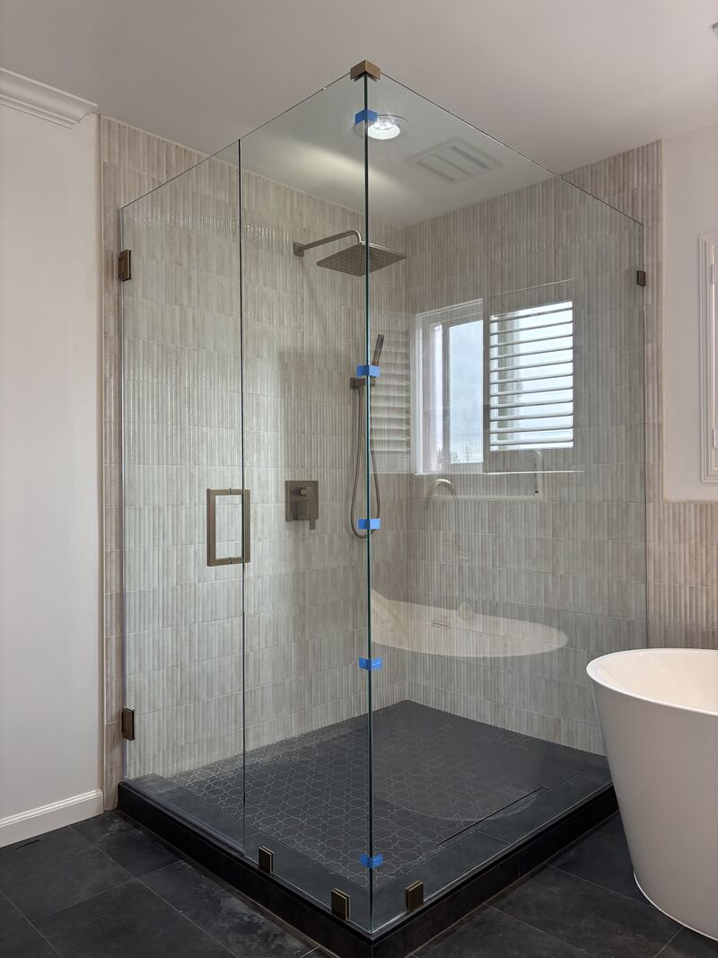 Finished frameless corner shower with FHC brushed-bronze hardware in Torrance