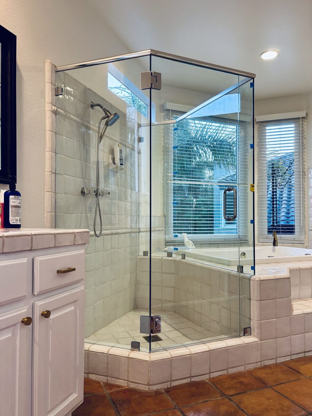 Frameless corner shower with a hinged glass door, fixed return panel and tiled curb